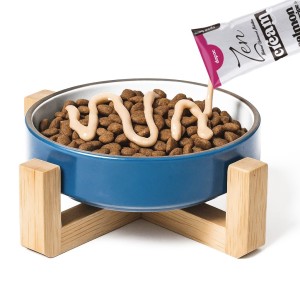 comedero de color azul repleto de comida seco para gato recibiendo crema de zen para gato.