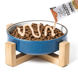 comedero de color azul repleto de comida seco para gato recibiendo crema de zen para gato.